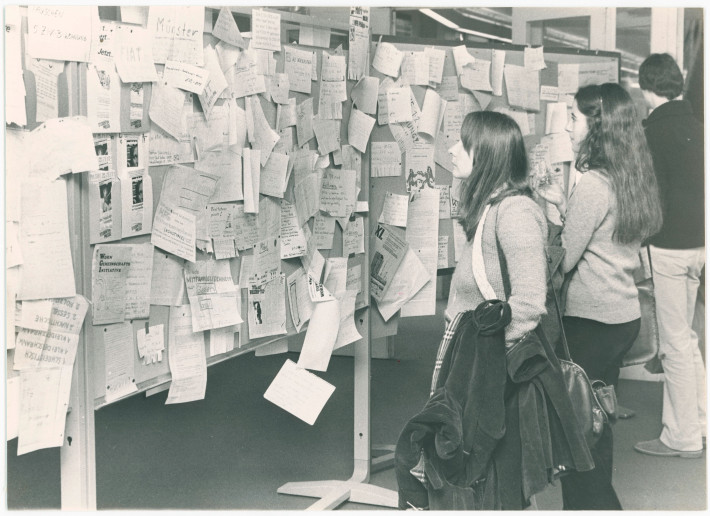 Studierende vor dem schwarzen Brett in der Rostlaube 